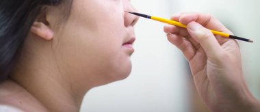 Güzel gelin, düğün gününde profesyonel makyözün düğün makyajını yapıyor. Saç tıraşındaki insanların bulanık görüntüsü. Kadın saçı. Kuaför, güzellik salonu..