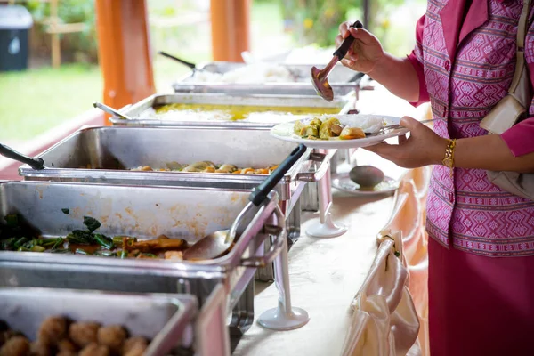 hands with a traditional food in the restaurant. Food Buffet Catering Dining Eating Party Sharing Concept. people group catering buffet food indoor in luxury restaurant with meat colorful fruits and vegetables