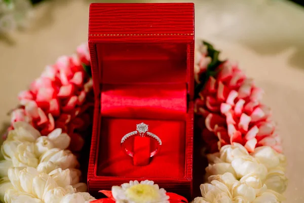 Elegant diamond ring in the box with flower background. Silver wedding rings in box. Diamond engagement ring isolated in box.