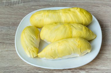 Beyaz bir tabağa yerleştirilmiş taze Durian meyvesi. Meyvelerin kralı Durian. Sarı renk beyaz tabakta. Tatlı tatlı ya da Tayland 'da atıştırmalık için olgun durian tropikal meyve yazı 