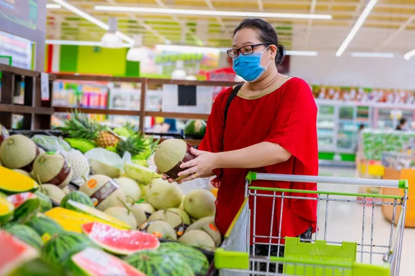 woman wearing a protective mask shopping during the pandemic. Emergency to buy list.food and supplies shortage. Protection measures while epidemic time. Preparation for a pandemic quarantine