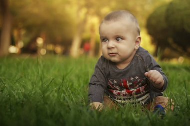 parkta çimlerde oturan çocuk