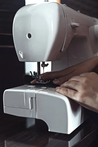 Female hands sew on a sewing machine