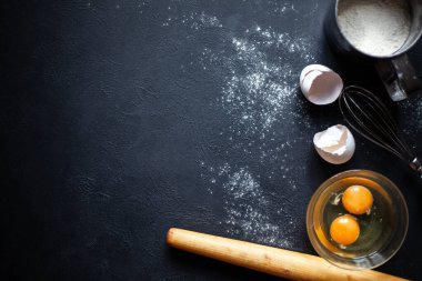 Yemek pişirme süreci. Un, yumurta, yumurta, yumurta, kabuk, çırpı, yuvarlanan iğne. Siyah beton zemine saçılmış un..