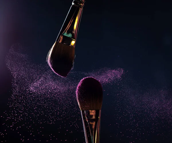 İmaj sanatı. İki profesyonel siyah makyaj fırçasının yakın plan fotoğrafı. Siyah arkaplanda mor toz ve fotokopi yeri var.. 