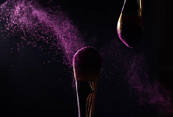 İmaj sanatı. İki profesyonel siyah makyaj fırçasının yakın plan fotoğrafı. Siyah arkaplanda mor toz ve fotokopi yeri var.. 