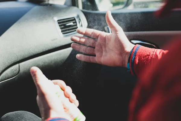 Arabadaki adam ellerini dezenfekte ediyor. Sıçrama görünüyor. Güneşli bir gün, karantina zamanı