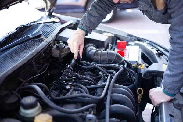Bir adam araba tamir ediyor. Makine parçaları.