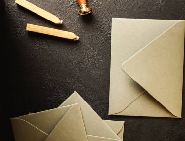 Üzerinde altın balmumu mühür, pul, kaşık ve siyah kağıt kaplama kartpostal olan boş zarflar. Tasarımın için bir model.