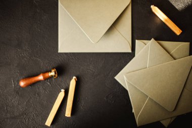 Üzerinde altın balmumu mühür, pul, kaşık ve siyah kağıt kaplama kartpostal olan boş zarflar. Tasarımın için bir model.