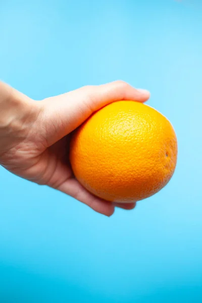 Bright orange in hand on a blue background