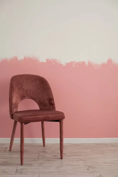 Bir sandalye, arkaplanda pembeli bir duvar.