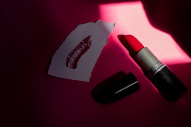 Pembe arka planda kırmızı ruj ve kağıda sürülmüş leke. Mesaj için yer. Düz yatıyordu