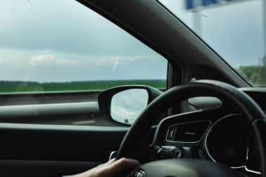 Adam araba kullanıyor. Arabanın penceresinden güzel bir doğa..