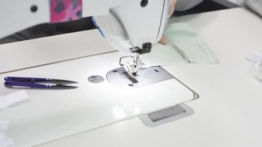 Tecrübeli bir terzi, salgın sırasında acil bir sipariş üzerine kumaştan koruyucu bir maske diker. Her kumaş parçası dikkatlice ve eşit şekilde dikilmeli, en küçük elementler bile mükemmel görünmeli..