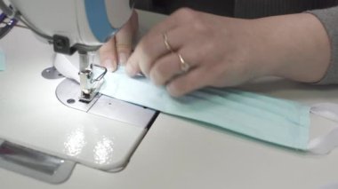 Tecrübeli bir terzi, salgın sırasında acil bir sipariş üzerine kumaştan koruyucu bir maske diker. Her kumaş parçası dikkatlice ve eşit şekilde dikilmeli, en küçük elementler bile mükemmel görünmeli..