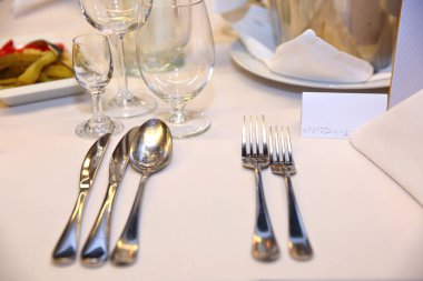 Kocaman bir masa, beyaz masa örtüsüyle kaplı çatal bıçak ve yiyeceklerle dolu..