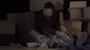 Orta yaşlı evsiz bir adam dürüm ve sosis aldı ve yemeğe başladı. Evsiz kaldığınızda, sokaktaki kahverengi karton kutular eviniz olur..