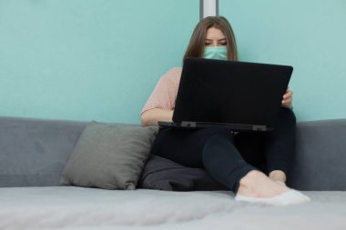 Akademik odada enfeksiyon riskini azaltmak için yüz maskesi takmalısınız. Genç, yatakhanedeki koruyucu maskeli bir yatakta oturuyor..