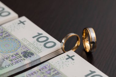 Yüzüklerin sembol olduğu düğün sırasında, bir mülkiyet intercyza 'sını tamamlamak da bazen gereklidir. Polonya banknotlarıyla çevrili altın alyanslar..