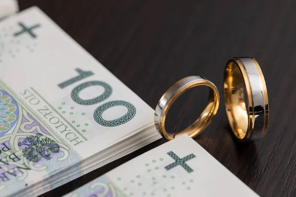 結婚式では リングがシンボルである場合によっては プロパティIntercyzaを締結する必要があります ポーランドの紙幣の山に囲まれた金の結婚指輪 — ストック写真