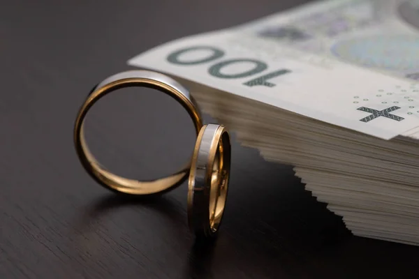 結婚式では リングがシンボルである場合によっては プロパティIntercyzaを締結する必要があります ポーランドの紙幣の山に囲まれた金の結婚指輪 — ストック写真