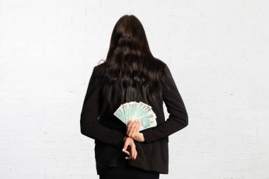 Kadının arkasında, kazanan kişiye sürpriz olsun diye para saklar. Kadın elinde çok sayıda kağıt banknotlar tutuyor..