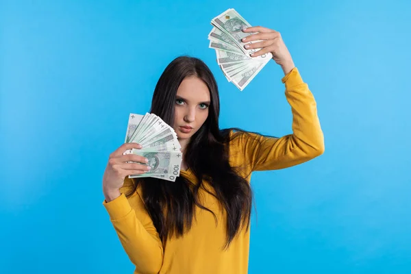 The teenager holds a large sum of money in her hand and is ready to give it to her. The young woman holds a fan of paper banknotes with a face value of one hundred zlotys.