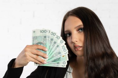 A young successful woman is holding a large amount of cash. Businesswoman holds Polish banknotes in a fan-shaped hands. clipart