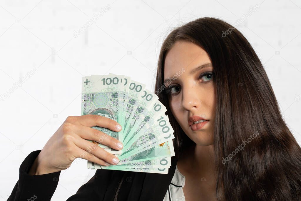 A young successful woman is holding a large amount of cash. Businesswoman holds Polish banknotes in a fan-shaped hands.