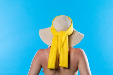 Sıcak yaz boyunca mavi gökyüzüne karşı kafasında büyük bir plaj şapkası vardı..