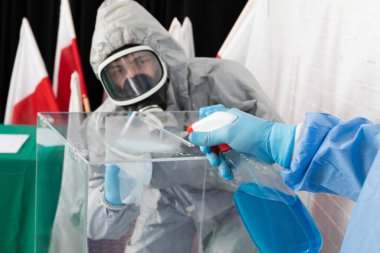 Polonya 'daki başkanlık seçiminden hemen önce oy sandığının iki kişi tarafından iyice kontrol edilmesi, temizlenmesi ve dezenfekte edilmesi.