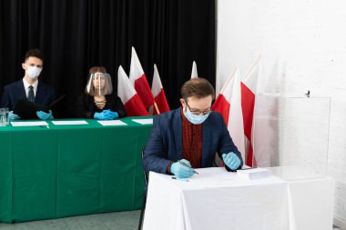 Adam, seçim kartının önündeki sandalyede oturuyordu. Bir aday seçer. Oy pusulasını doldurur.