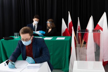 Adam, seçim kartının önündeki sandalyede oturuyordu. Bir aday seçer. Oy pusulasını doldurur.