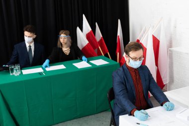 Adam, seçim kartının önündeki sandalyede oturuyordu. Bir aday seçer. Oy pusulasını doldurur.