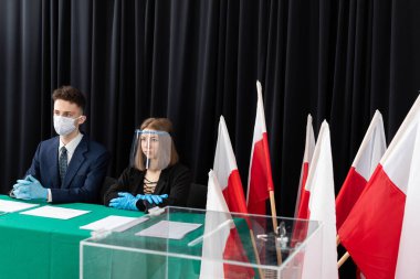 Genç bir adam ve genç adam bir masada oturmuş seçmenleri bekliyorlar..