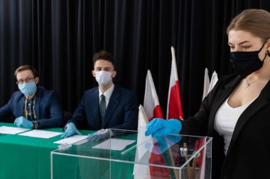 Oy sandığı. İçinde oy pusulası olan bir zarf. Tamamlanmış oy pusulasını bir zarfın içinde sandığa atıyor..