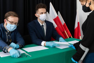 Oy sandığı. İçinde oy pusulası olan bir zarf. Tamamlanmış oy pusulasını bir zarfın içinde sandığa atıyor..