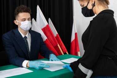 Oy sandığı. İçinde oy pusulası olan bir zarf. Tamamlanmış oy pusulasını bir zarfın içinde sandığa atıyor..