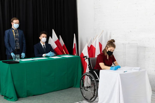 An adult teenager is in a wheelchair at a polling place. No barriers for wheelchairs.
