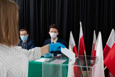 Oy sandığı. İçinde oy pusulası olan bir zarf. Tamamlanmış oy pusulasını bir zarfın içinde sandığa atıyor..