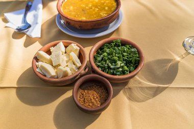 Locro, tipik Arjantin yemekleri, yanında ekmek ve bir bardak şarap, kaşıklarla..