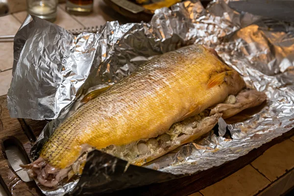 Peixe dorado grelhado caseiro com legumes embrulhados em folha de alumínio na mesa rústica. Vista superior . — Fotografia de Stock