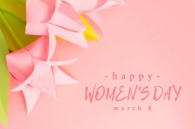 Kağıt origami el yapımı lalelerle pembe zemin üzerine Mutlu Kadınlar Günü metni. 8 Mart tebrik kartı. Tatil ve hediye konsepti