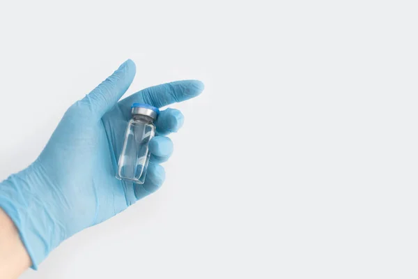 医師は 青いカバーと灰色の背景にクリア流体と青いゴム手袋薬瓶を保持手 コロナウイルスワクチン開発 2019 Ncv液体薬 ウイルス解毒剤 スペースのコピー — ストック写真