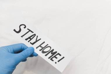 Beyaz arka planda karantina mesajı taşıyan mavi lastik eldivenli bir kadın. Evde kal. Çin 'de Coronavirus. 2019-NCoV. Kendini izole etme ve koruma kavramı. Boşluğu kopyala