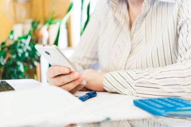 Beyaz cep telefonu kullanan bir kadın. Evde, iş yerinde çalışan bir kadın. Öğretmen uzaktan öğretiyor. Çevrimiçi eğitim ve uzaktan çalışma kavramı. Sosyal mesafeler koronavirüsü veya covid-19 'u korur