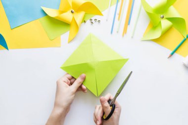 Evde çocuklarla kağıt yeşili yel değirmeni oyuncağı yapmayı. Adım adım talimatlar. Eller DIY yaz projesi yapıyor. Beşinci adım. Merkezde daire çizmek için çizgileri kes, yarım üçgen al