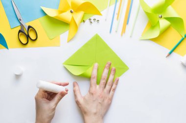 Evde çocuklarla kağıt yeşili yel değirmeni oyuncağı yapmayı. Adım adım talimatlar. Eller DIY yaz projesi yapıyor. Üst Manzara. Yedinci adım. Çemberin ortasında tutkal köşesi