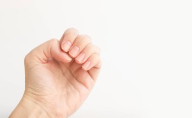 Yumuşak kare şeklinde tırnakları olan kadın eli parmaklarında bir şey tutuyor. Kadın sanal nesneyi saklar. Evde çivi bakımı. Boşluğu kopyala